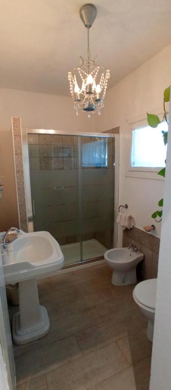 a bathroom with a chandelier and a sink and a toilet at Message in a Bottle Bed and Breakfast in Camporosso