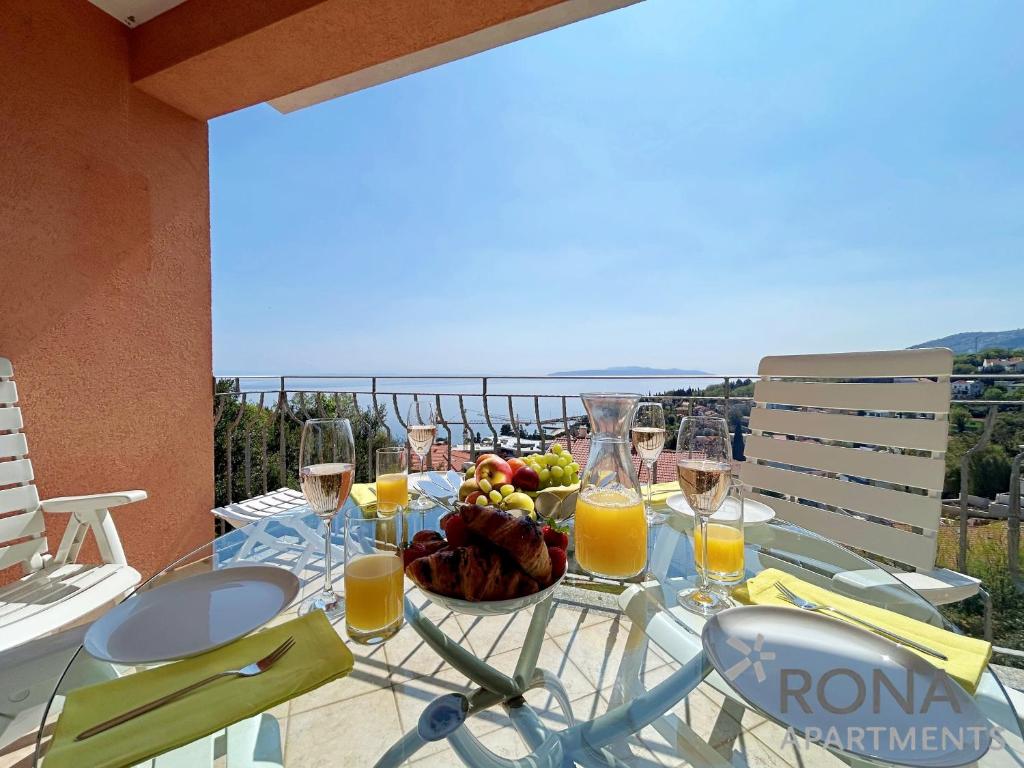 a glass table with a bowl of fruit and glasses of orange juice at Rona Spacious apartment with a panoramic view in Ičići