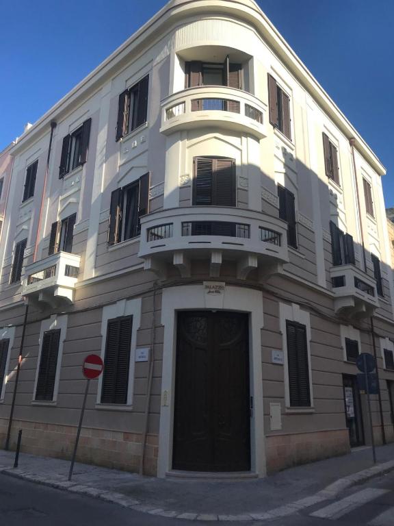 a white building with a black door on a street at Palazzo Annarita in Brindisi