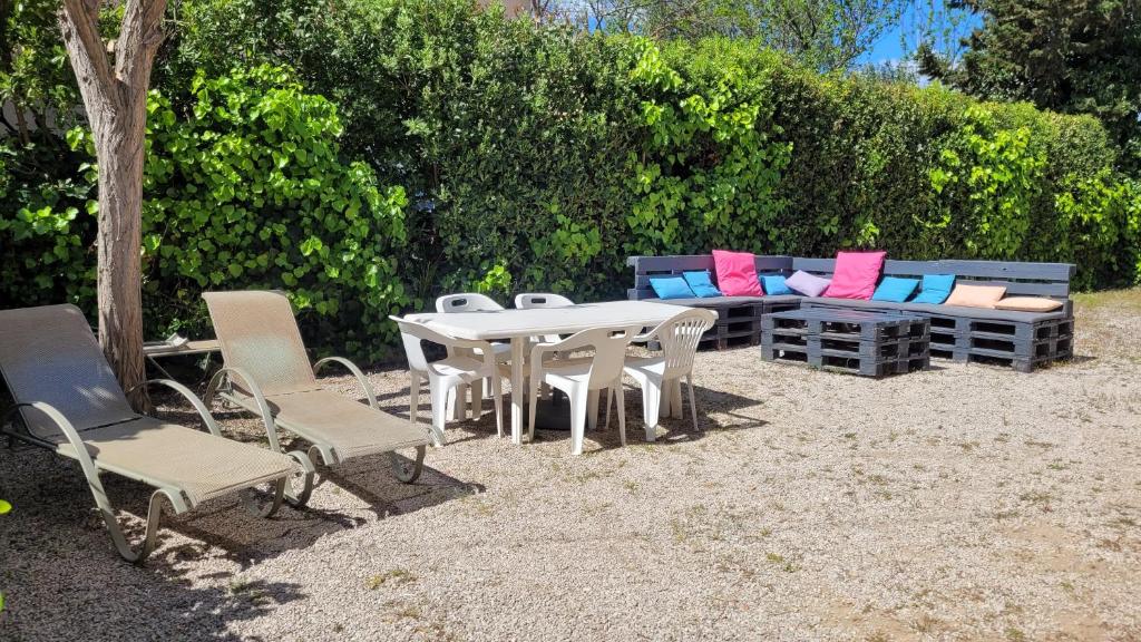 une table et des chaises et un canapé avec des coussins colorés dans l'établissement T3 jardin, parking, terrasse à 80 m de la plage à Saint cyr sur mer, aux Lecques