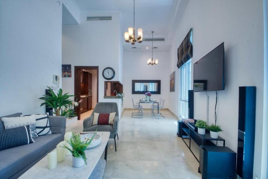 a living room with two couches and a tv at The Smart Concierge - Delphine in Dubai