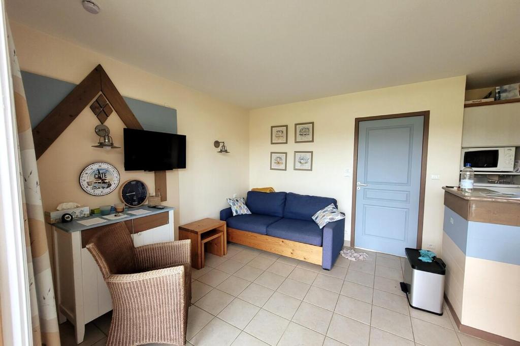un salon avec un canapé bleu et une télévision dans l'établissement Maison Belle Dune L'Ile Aux Oiseaux 28, à Quend-Plage