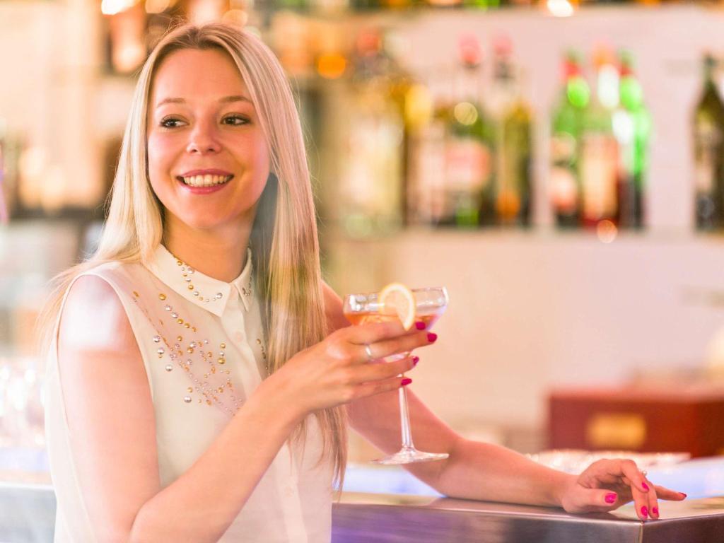 a woman is smiling while holding a glass of wine at Novotel Porto Gaia in Vila Nova de Gaia