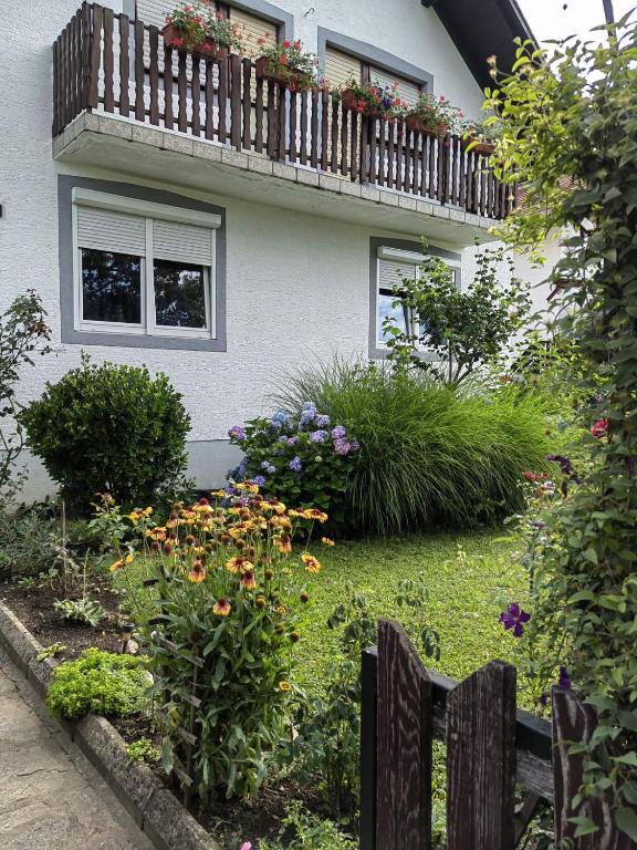 a house with a balcony with flowers and a fence at Apartman Barbara in Grabovac