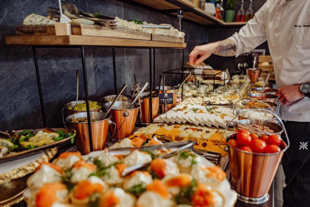 Buffet spread with cheeses, appetizers, metal serving buckets and chef arranging items.