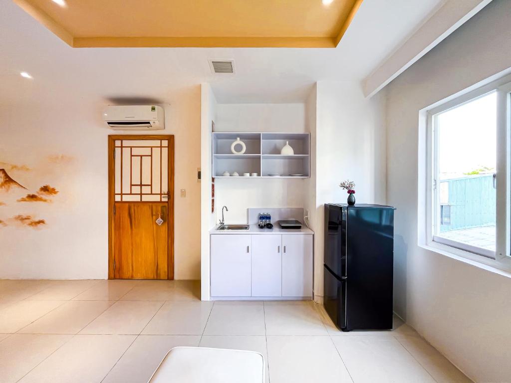 A compact in-room kitchenette with a refrigerator, sink, kettle and window.