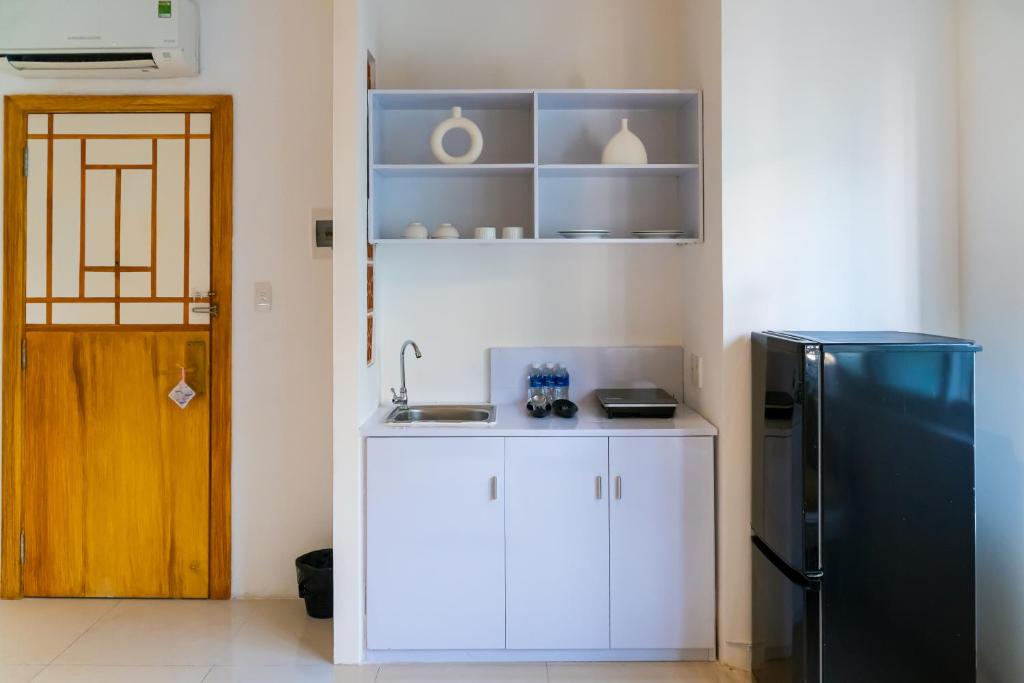 A compact kitchenette with a sink, cabinets and full-height refrigerator.