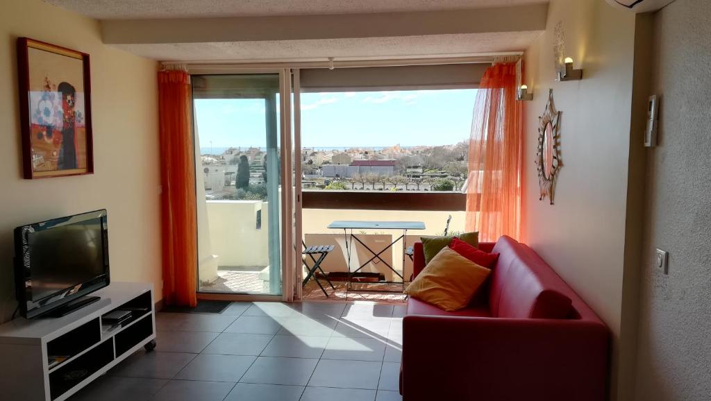 un salon avec un canapé rouge et une télévision dans l'établissement CapNat - Village Naturiste - Port Nature - Le Chili Pepper, au Cap d'Agde