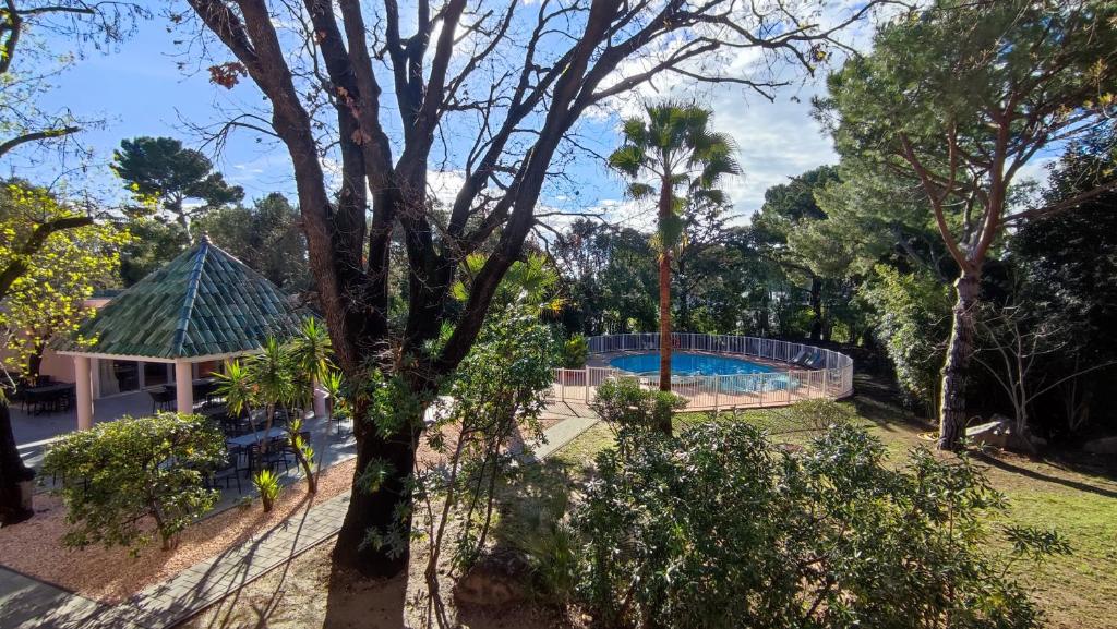 a resort with a swimming pool and a tree at Kyriad Cannes - Mandelieu in Cannes