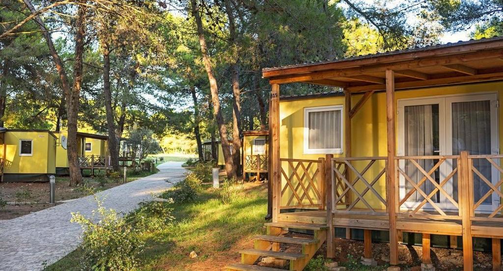 a small yellow cabin in the middle of a road at Mobile Home Kamp Pineta - IB Studio in Fažana