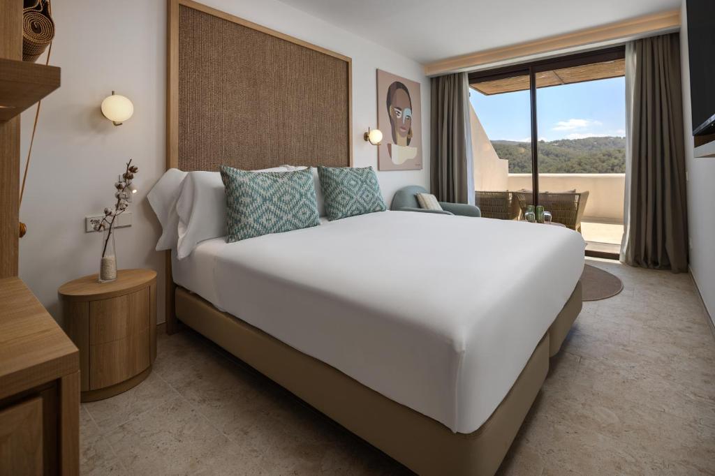 a bedroom with a large white bed and a window at Cala San Miguel Ibiza Resort, Adults only, Curio Collection by Hilton in Puerto de San Miguel