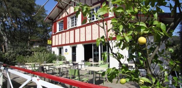 un bâtiment avec des tables, des chaises et un arbre dans l'établissement Paloma, à Hossegor