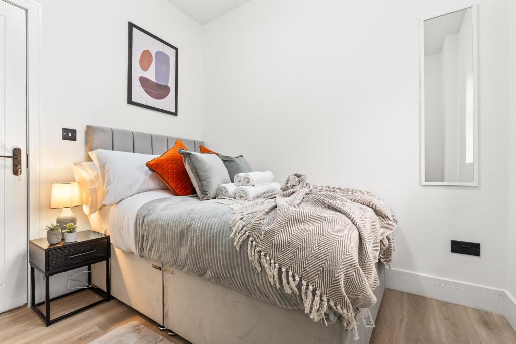 a bedroom with a bed with orange and gray pillows at Stunning 4 Bed, Sleeps 10, Parking in London