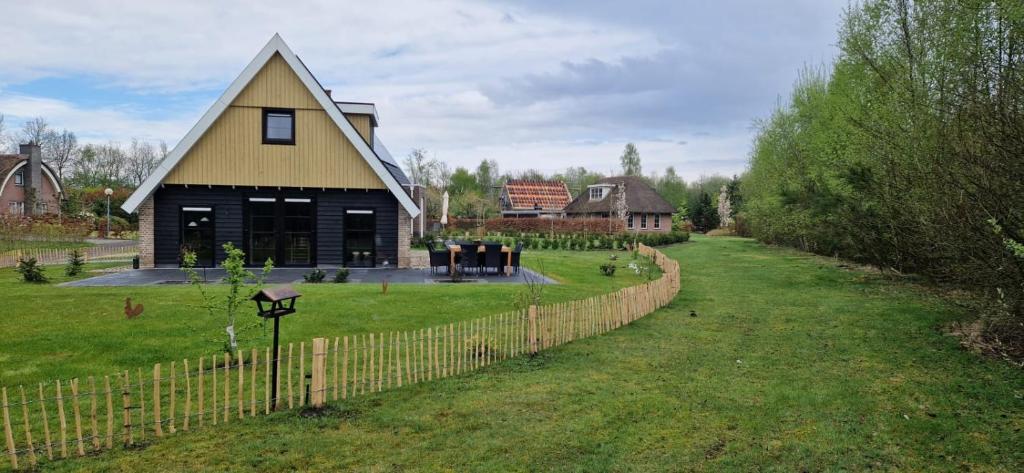 a house with a fence in front of a yard at Villa Linde | 4 personen - Vakantiepark De Kremmer in Gasselte