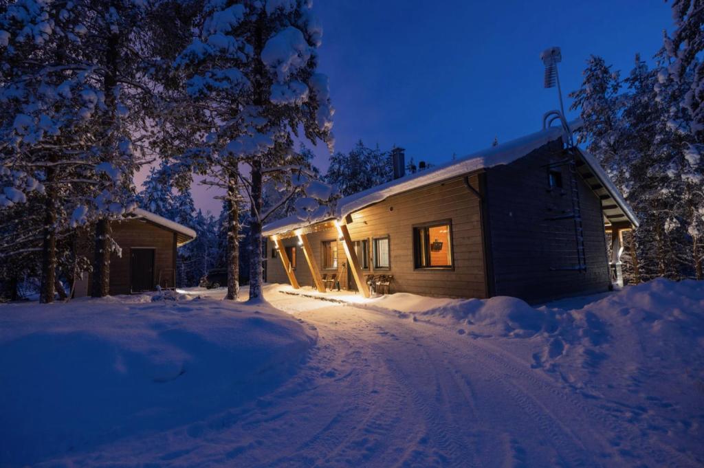 una cabaña de madera en la nieve por la noche en Käenpesä, en Kuusamo