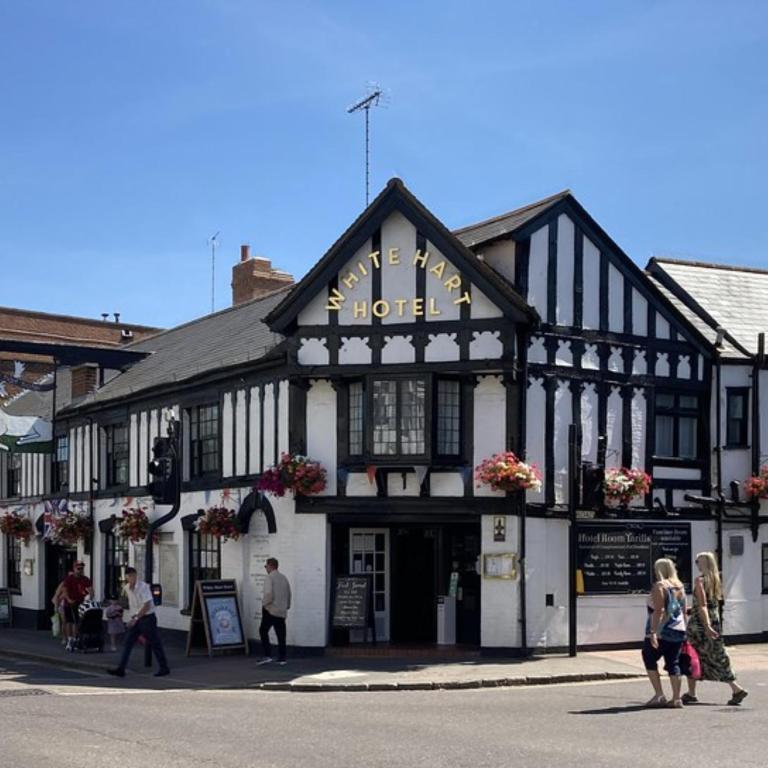 a black and white building with people walking in the street at The White Hart Hotel Witham in Witham