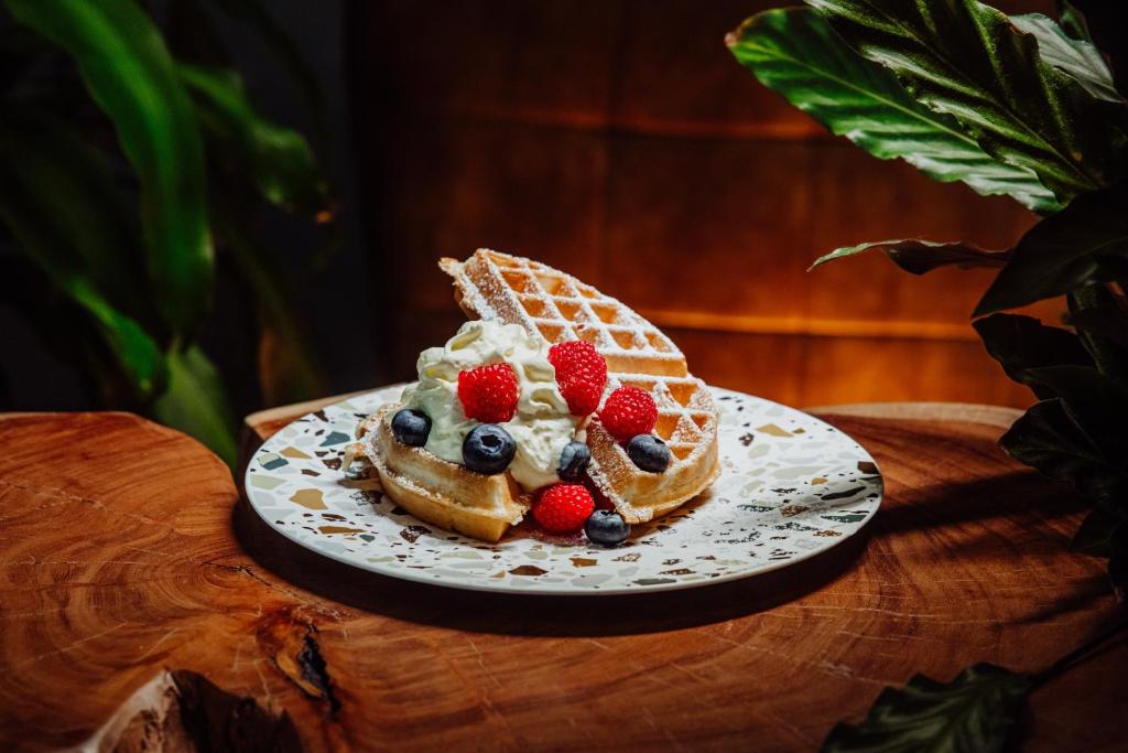 Warm dessert plate with Belgian waffle, whipped cream and fresh berries on wooden table