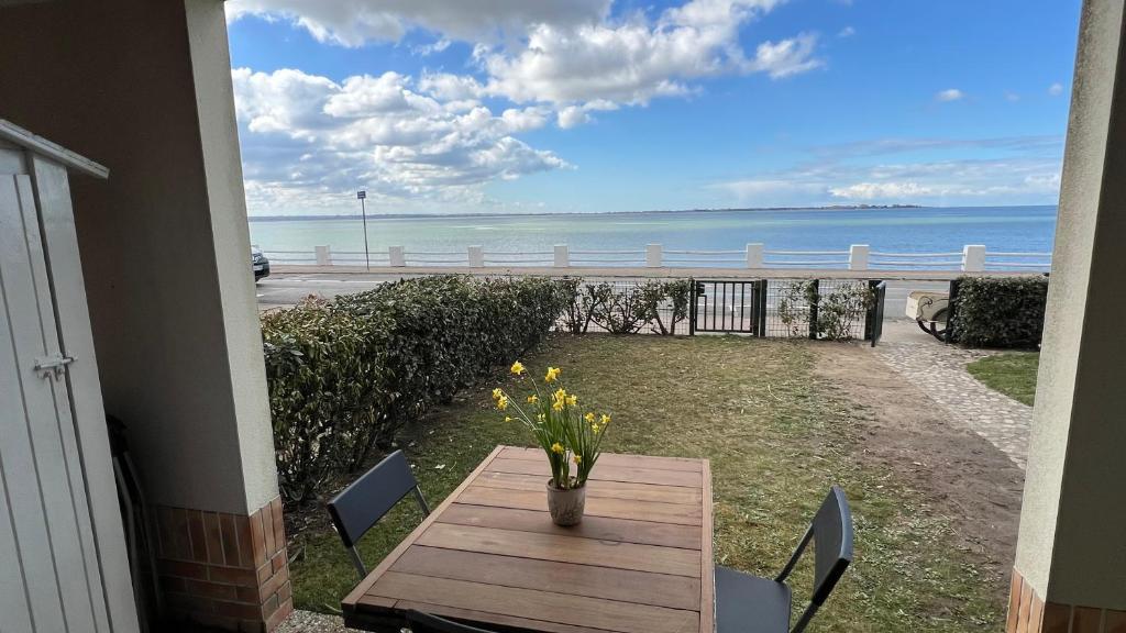 - une table avec un vase de fleurs sur le balcon donnant sur l'océan dans l'établissement Le Jean Bart front de mer, au Crotoy