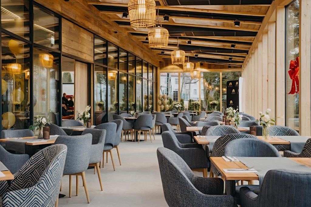 Bright, wood-accented restaurant with rows of grey upholstered chairs and hanging lamps