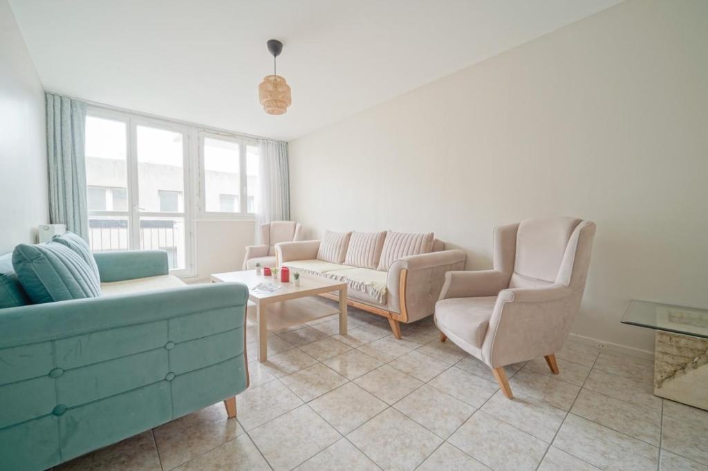 un salon avec un canapé, des chaises et une table dans l'établissement appartement saint ouen sur Seine, à Saint-Ouen