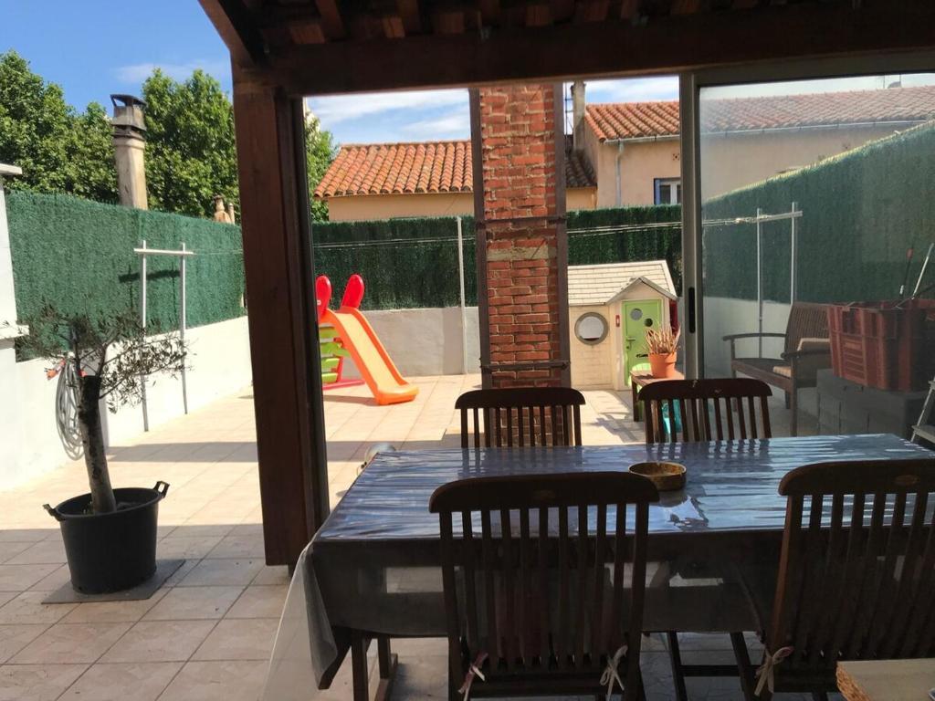 une terrasse avec une table et des chaises ainsi qu'une aire de jeux dans l'établissement Appartement avec grande terrasse plein sud, à Perpignan