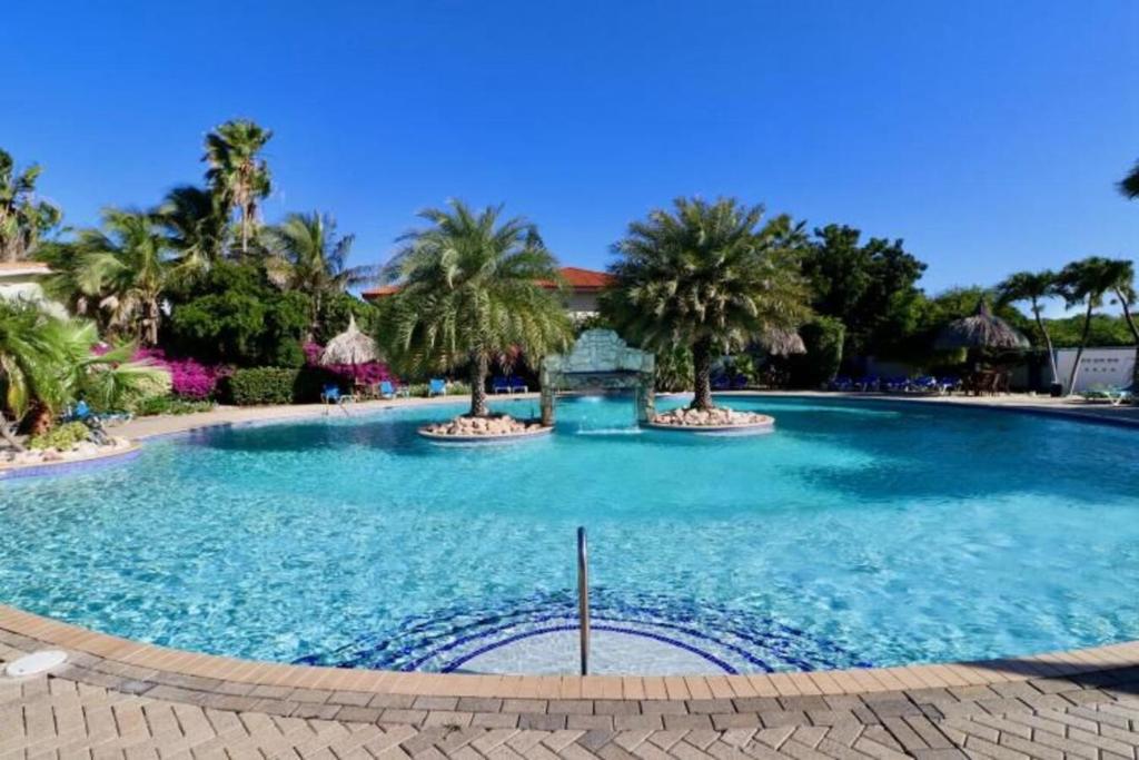 a large swimming pool with palm trees in it at Seru Coral Resort Appartement 188 in Willemstad