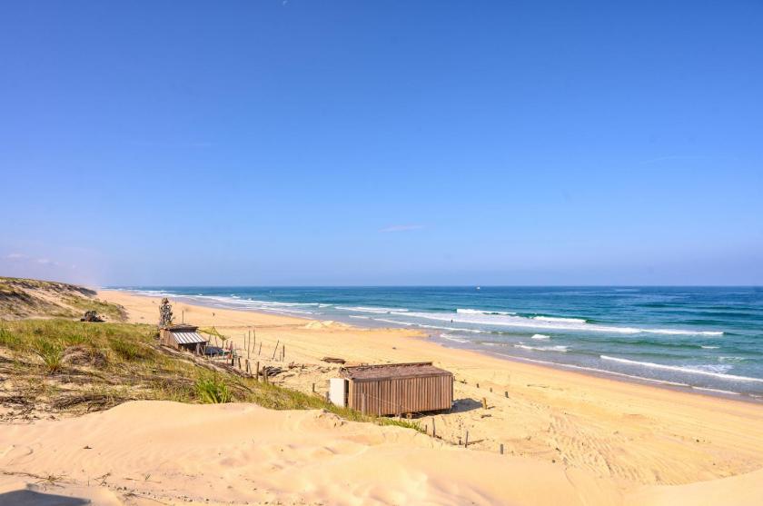 une plage avec des bâtiments sur le sable et l'océan dans l'établissement le m130, à Bias