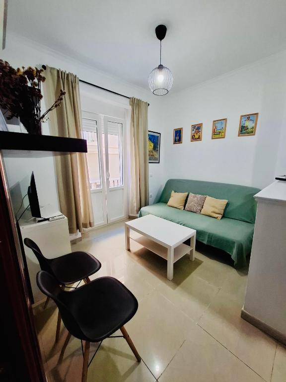Una sala de estar con un sofá verde y una mesa. en Apartamento Feduchy, en Cádiz