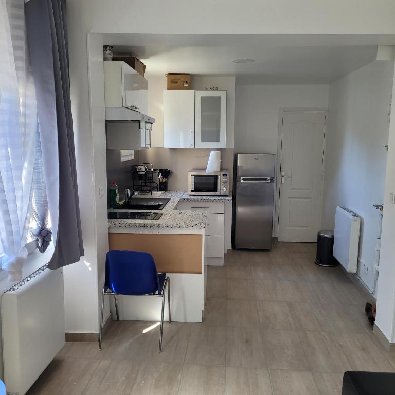 a small kitchen with white cabinets and a blue chair at Maison pour 4 personnes à 2 pas de Paris superficie 40m2 in Bondy
