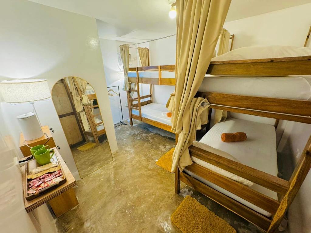 een kamer met 3 stapelbedden en een spiegel bij Fazzah De Siargao in General Luna