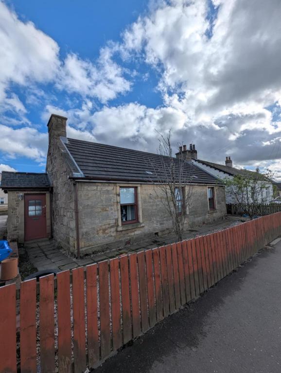 a brick house with a fence in front of it at The Cottage in Kirk of Shotts