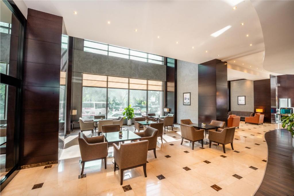 una sala da pranzo con tavoli, sedie e finestre di Millennium Central Doha a Doha
