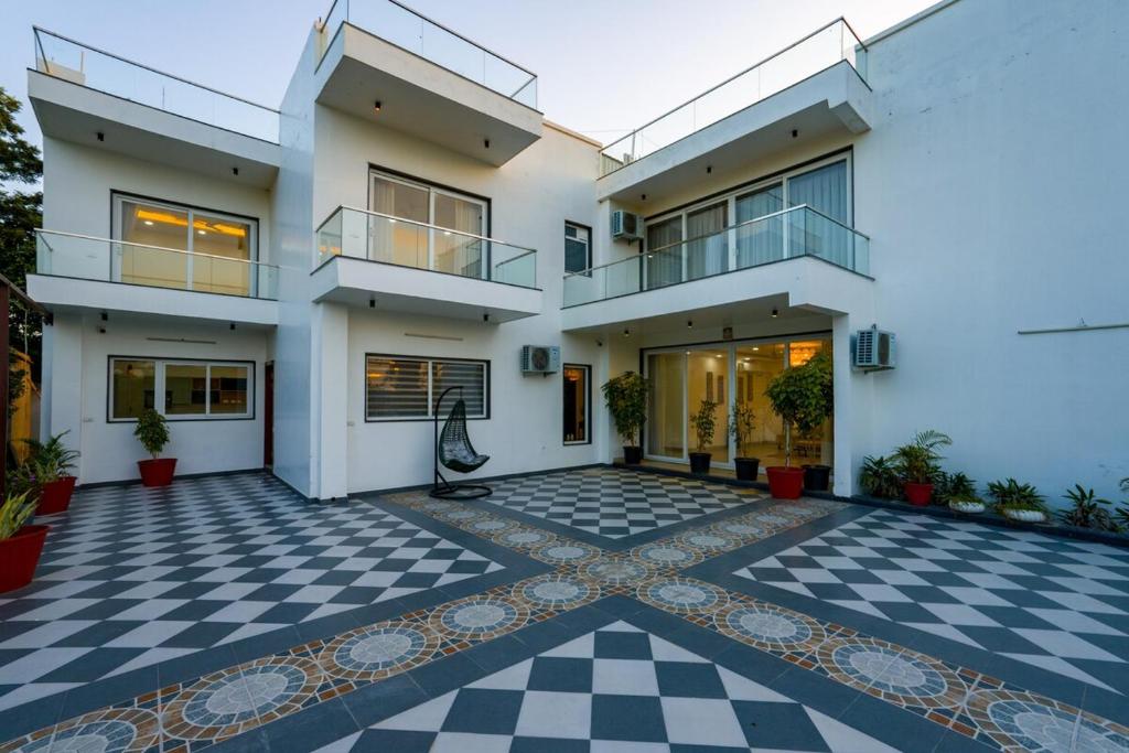 an exterior view of a house with a checkered floor at ELIVAAS AdhiVa 5-BHK Farmhouse with Private Pool, Bar & Lush Garden in Bahora