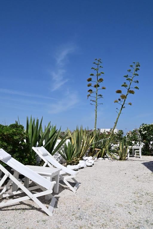 two white lounge chairs sitting on a beach at She Mykonos - The Iconic Windmill in Megali Ammos