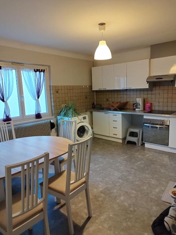 une cuisine avec une table et des chaises dans une pièce dans l'établissement Appartement centre Alsace, à Kertzfeld