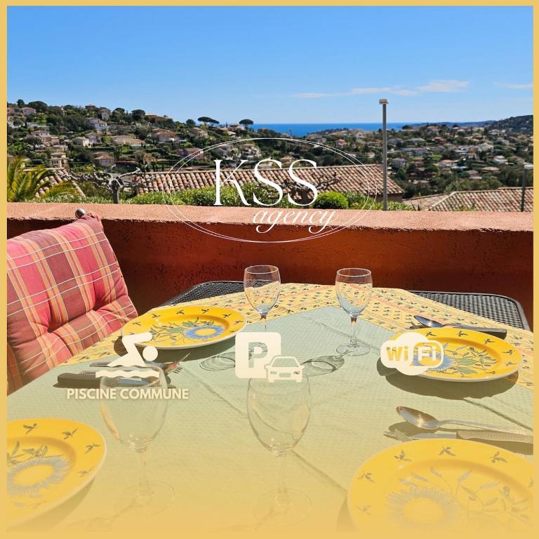 une table avec des assiettes et des verres à vin sur un balcon dans l'établissement Mazet vue mer - parking - wifi - clim - piscine, à Sainte-Maxime