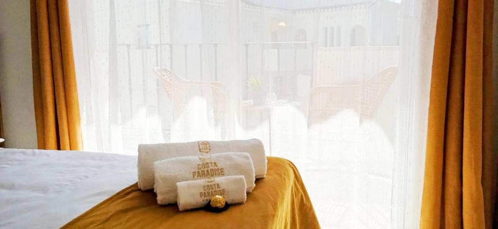 two folded towels on a bed in front of a window at The Seven Seas in Benalmádena