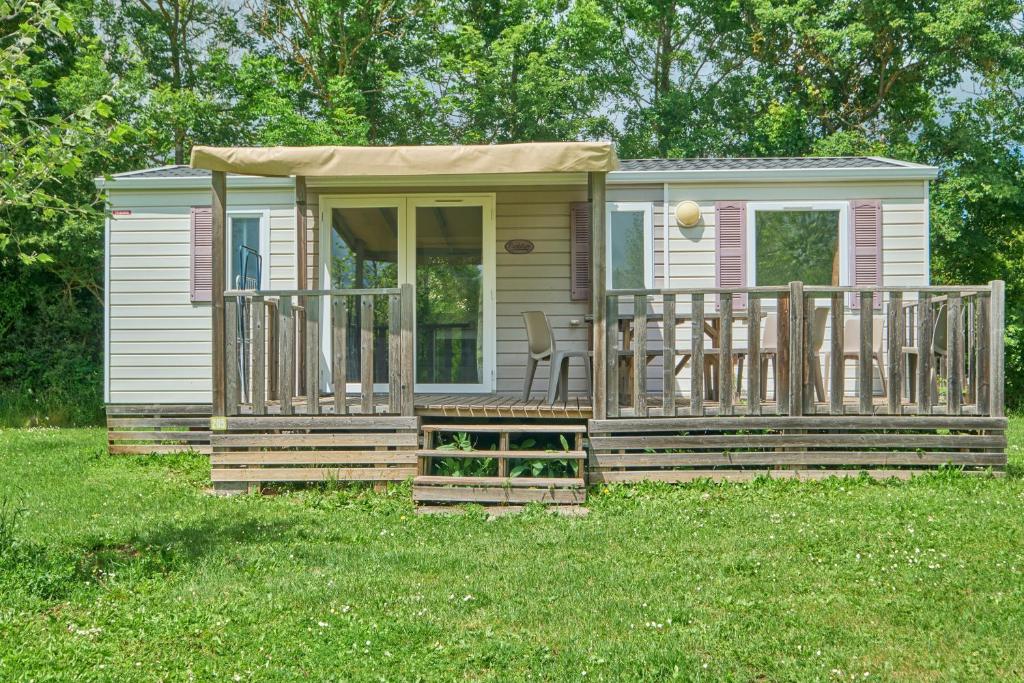 une petite maison avec un porche et une terrasse dans l'établissement Mobil Home 6 personnes 206, à Mens