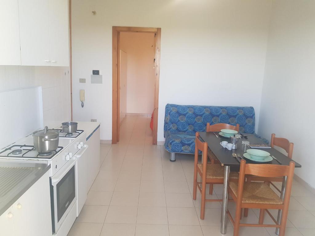 a kitchen with a table and chairs and a couch at Bilocali Baia Verde in Baia Verde