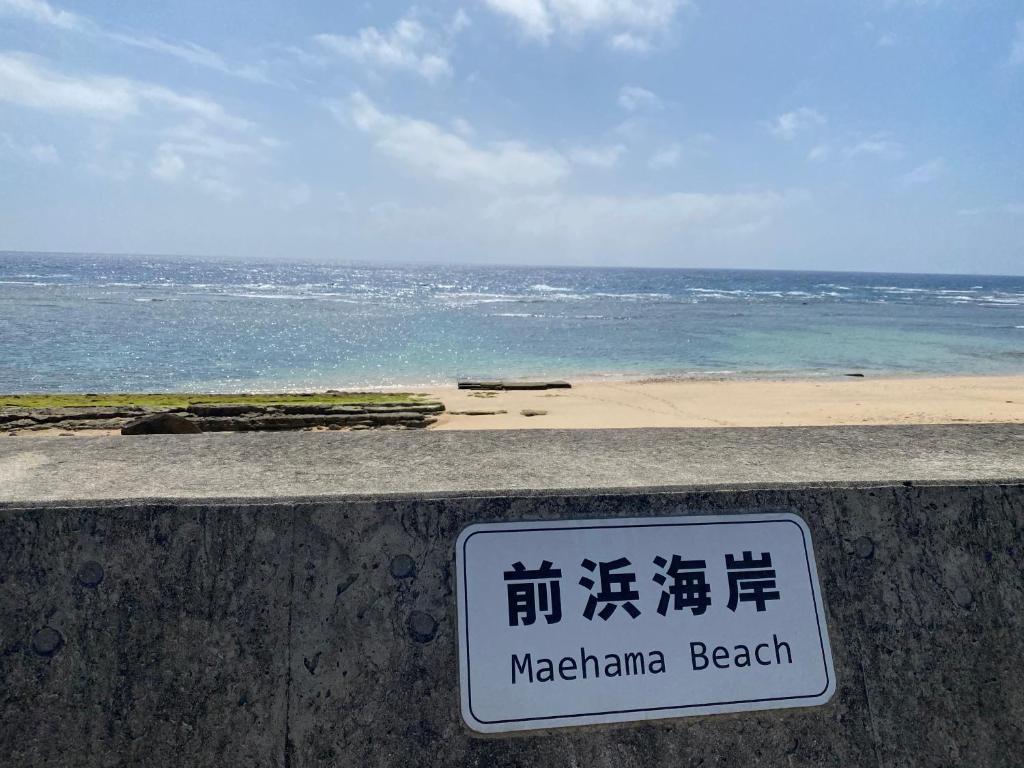 a sign on a wall with a beach in the background at Lagoon藍yoron 一棟貸し in Yoron