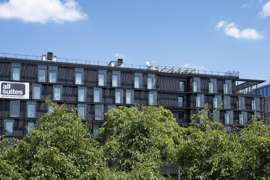 巴黎All Suites Appart Hôtel et Hôtel - Paris 13 - Porte d'Italie的前面有树木的办公楼
