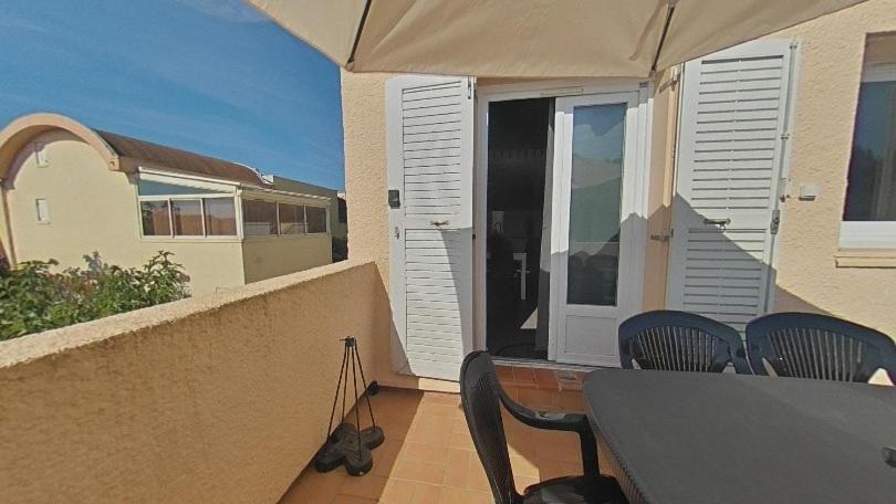 - un balcon avec des chaises, une table et un parasol dans l'établissement Cammari's logement pour 6 personnes proche plage et port, à Gruissan