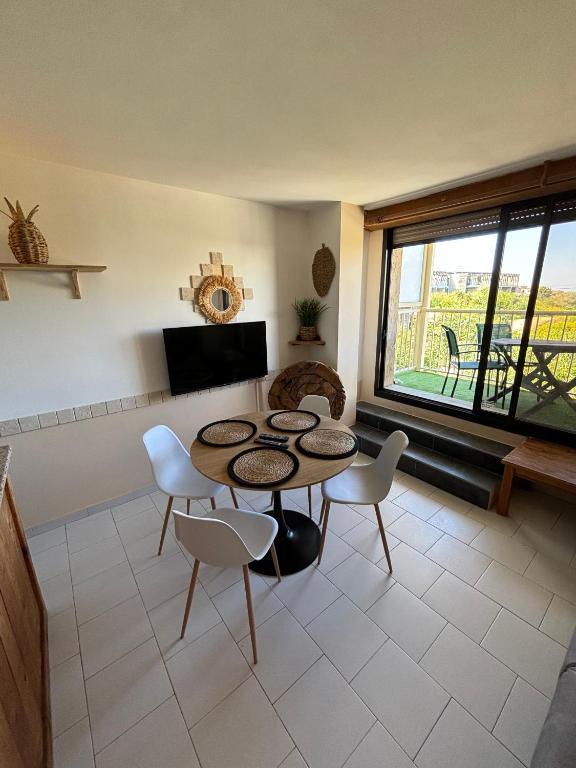 un salon avec une table et des chaises et une fenêtre dans l'établissement Le Petra Paoli - Appt climatisé avec piscine, à LʼÎle-Rousse