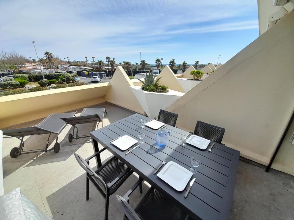un patio avec une table et des chaises sur un balcon dans l'établissement Appartement Rosy Village Naturiste, au Cap d'Agde