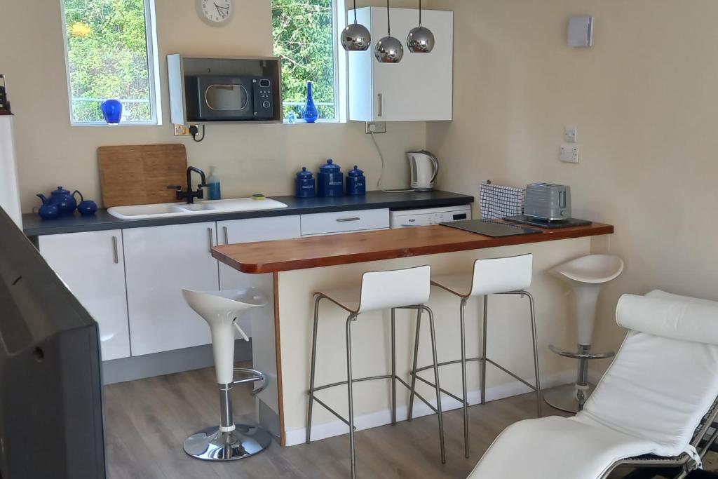 a kitchen with a bar with stools and a microwave at Bali Hi Cliff Cottage-Sleeps 2-Hot Tub-5MinBeach in Sheerness