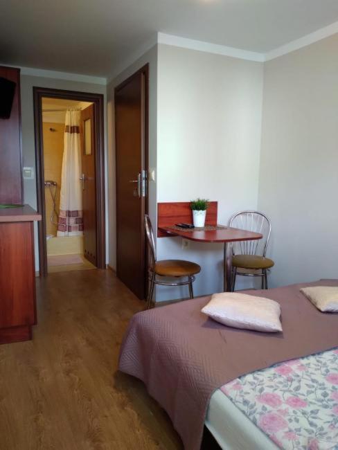 a bedroom with a bed and a table and a dining room at Pokoje "Pod ósemką Mielno" in Mielno
