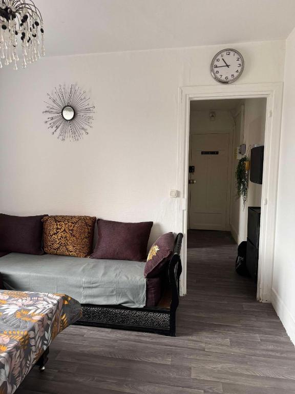 un salon avec un canapé et une horloge au mur dans l'établissement Appartement RIS ORANGIS, à Ris-Orangis