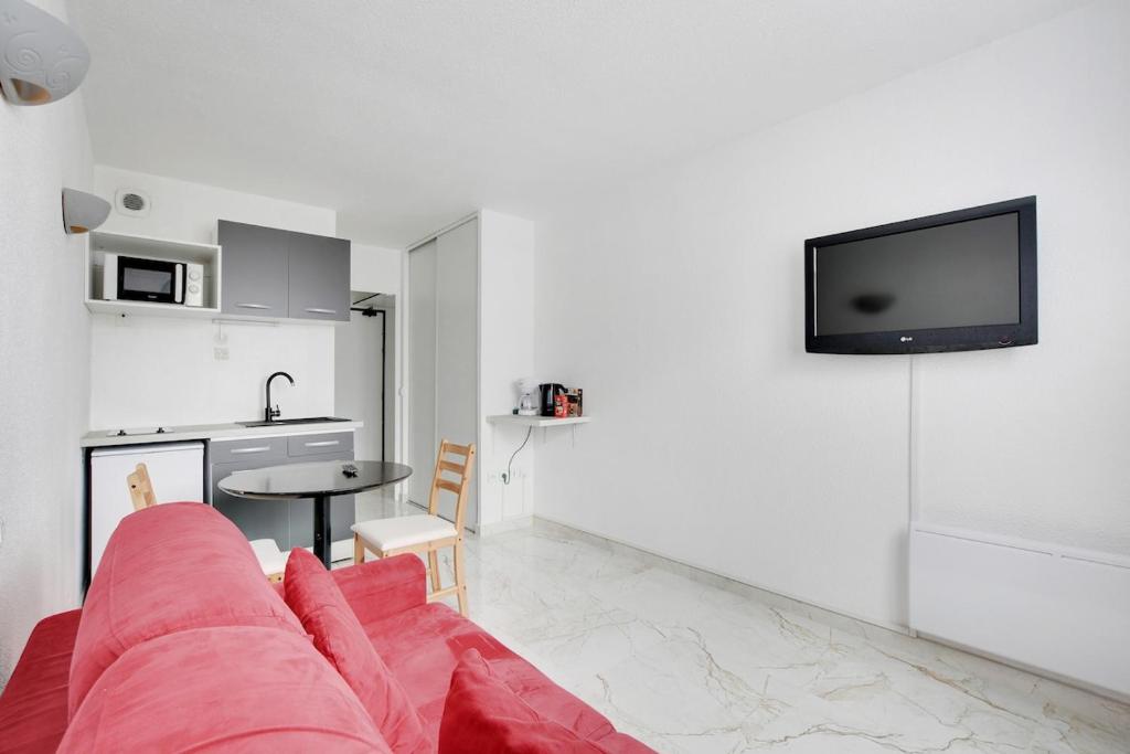 un salon avec un canapé rouge et une cuisine dans l'établissement Nice & Quiet Studio - Saint Denis, à Saint-Denis