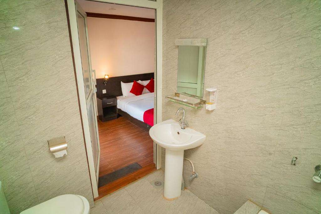 bagno con lavandino e letto con specchio di Hotel Juju a Pokhara