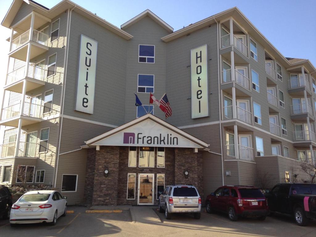 un gran edificio de apartamentos con coches aparcados frente a él en Franklin Suite Hotel, en Fort McMurray